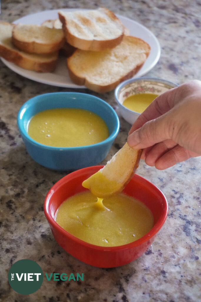 a toast stick dipped into the vegan egg yolk sauce