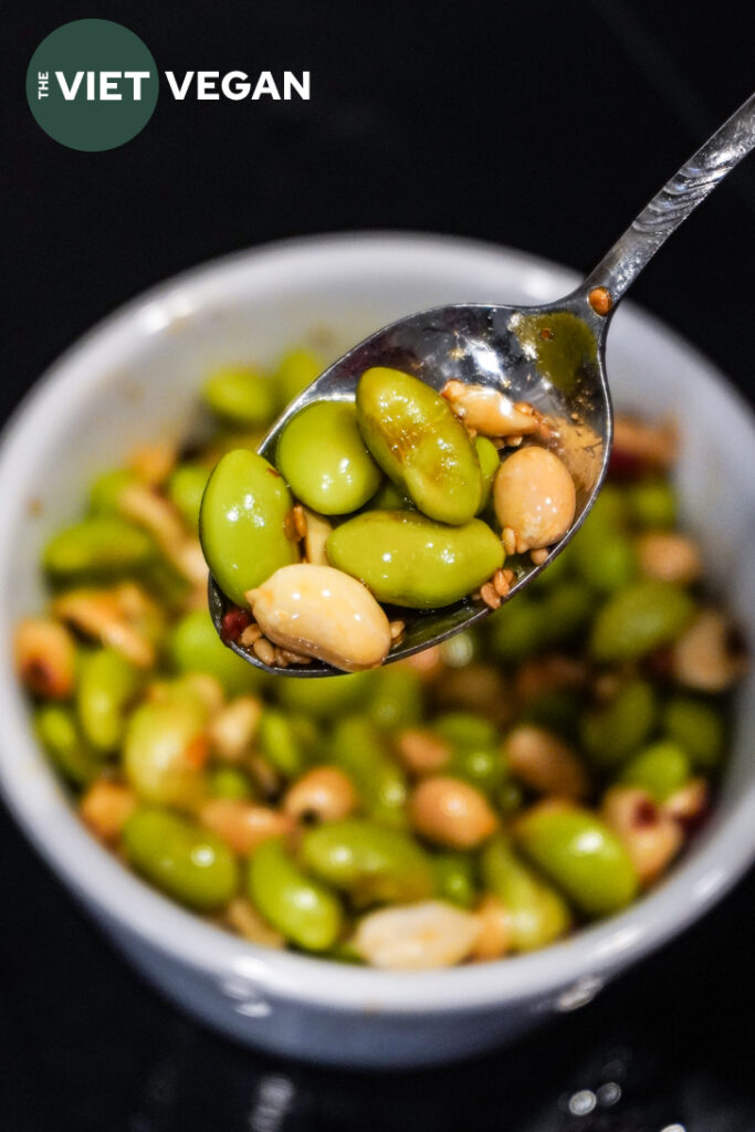 Crunchy edamame peanut salad in a spoon with toasted sesame seeds