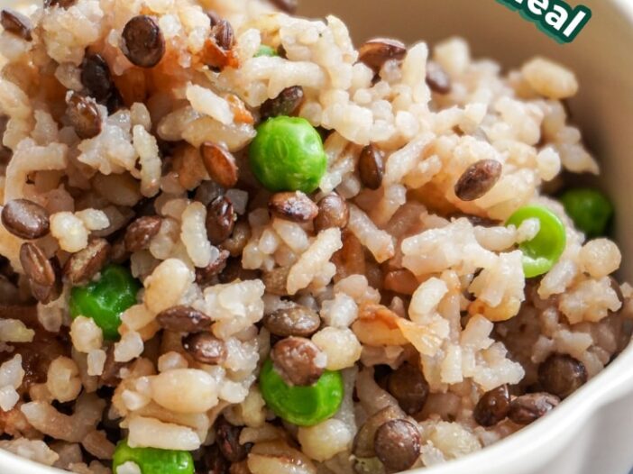 close up of lentil barley rice with peas in a cream scalloped bowl