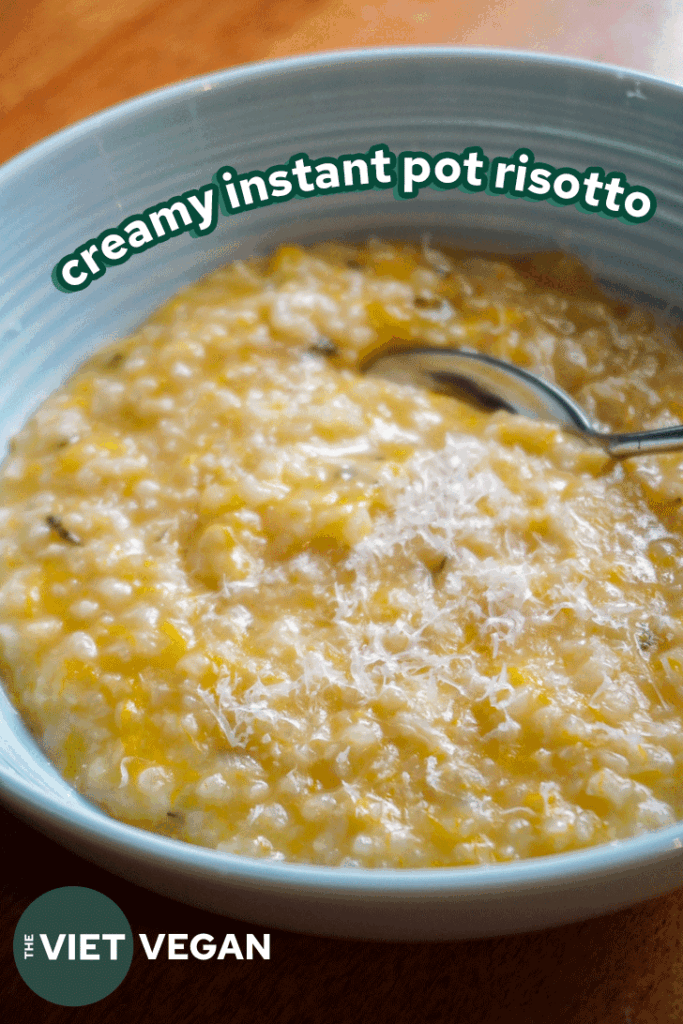 a bowl of golden risotto in a light blue bowl with a silver spoon.
