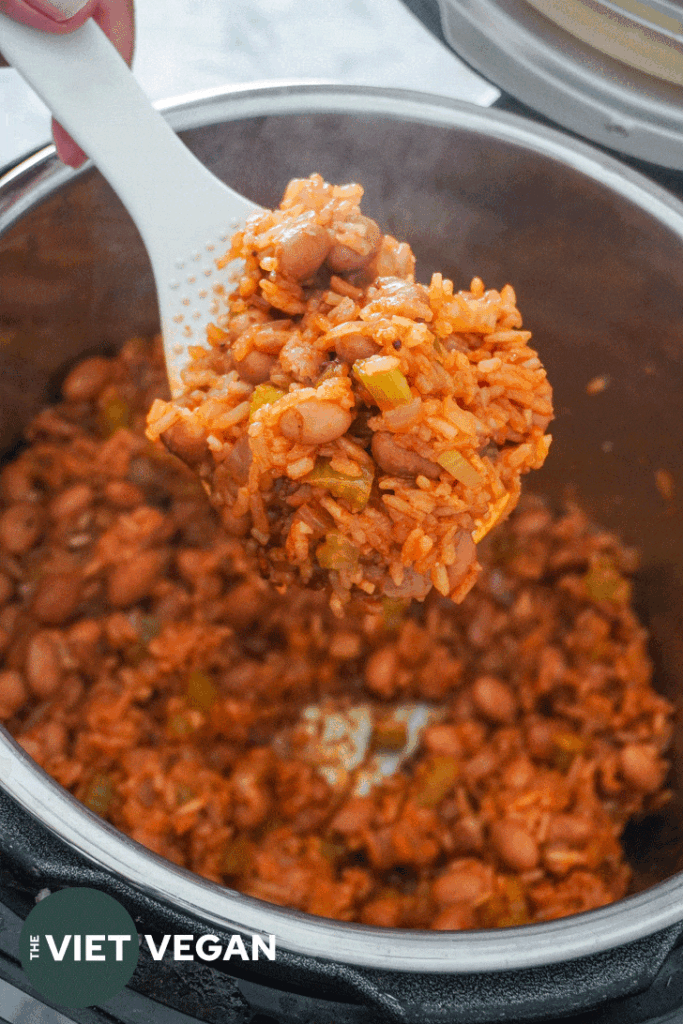 red rice and beans on a rice paddle over the instant pot.