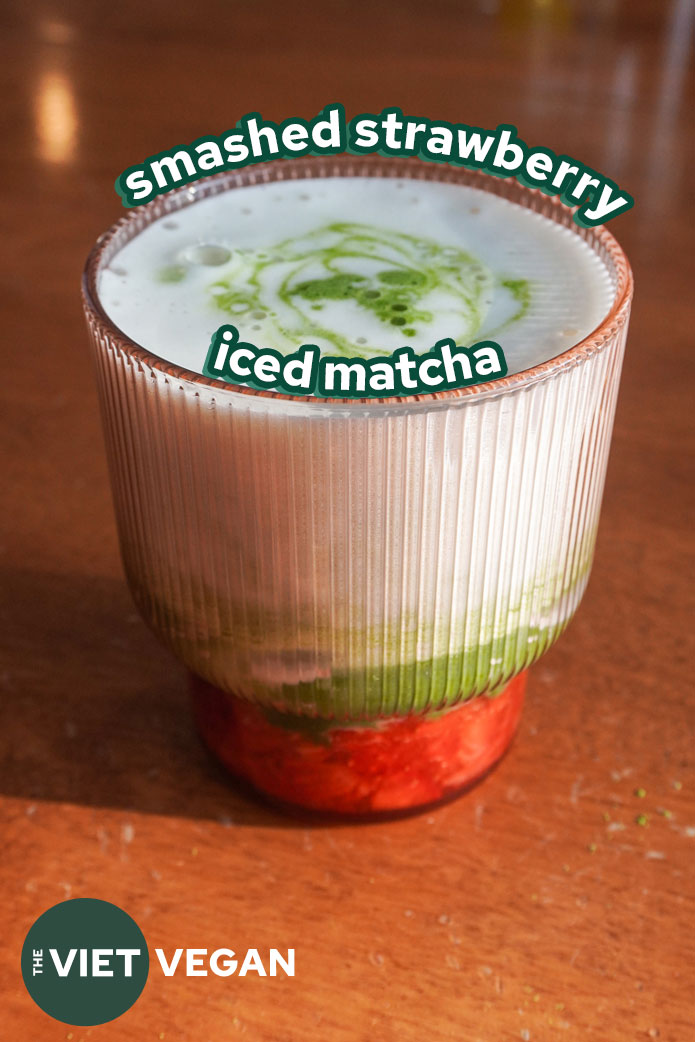a ribbed pink glass with smashed strawberries and an iced matcha drink